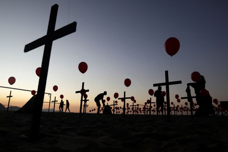 Siluetas de gente entre cruces y globos colocados por miembros de la ONG Río de Paz en homenaje a las cien mil víctimas mortales de la enfermedad COVID-19 en el país, en la playa de Copacabana en Río de Janeiro