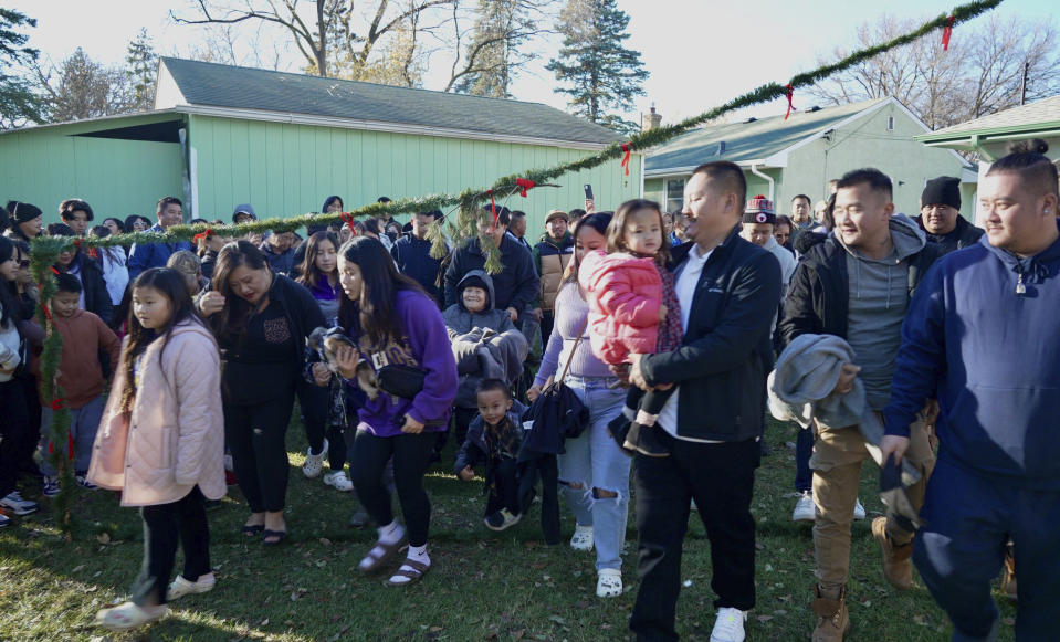 Family, friends and members of the Twin Cities Hmong community gather in the backyard of Nhia Neng Vang for a Hmong New Year sweeping ritual in St. Paul, Minn. on Saturday, Nov. 18, 2023. The ritual, in which participants walk together in circles, first to the west and then to the east, represents leaving old negative spirits behind and embracing the new year. (AP Photo/Mark Vancleave)