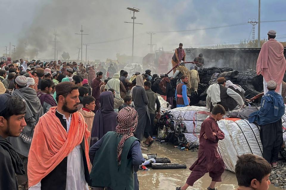 People gather beside a burnt truck caused by Afghan forces shelling, in Chaman, a town in Pakistan's southwestern along Afghan border, Sunday, Dec. 11, 2022. Pakistan's military condemned the "unprovoked and indiscriminate fire" of heavy weapons by Afghan forces on civilians in a border town Sunday, saying some people killed and more than dozen wounded in the incident. (AP Photo)