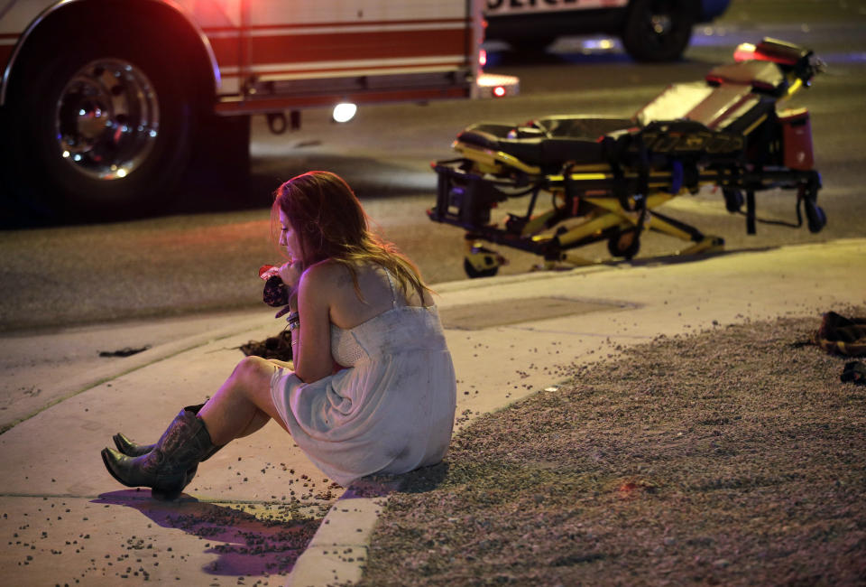 FILE - A woman sits on a curb at the scene of a shooting outside a music festival on the Las Vegas Strip in Las Vegas on Oct. 2, 2017. The Supreme Court has struck down a Trump-era ban on bump stocks, a gun accessory that allows semiautomatic weapons to fire rapidly like machine guns. They were used in the deadliest mass shooting in modern U.S. history. The high court found the Trump administration did not follow federal law when it reversed course and banned bump stocks after a gunman in Las Vegas attacked a country music festival with assault rifles in 2017.(AP Photo/John Locher, File)