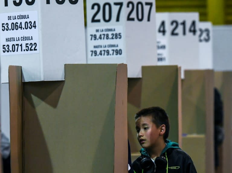 A boy watches a relative vote at a polling station in Bogota