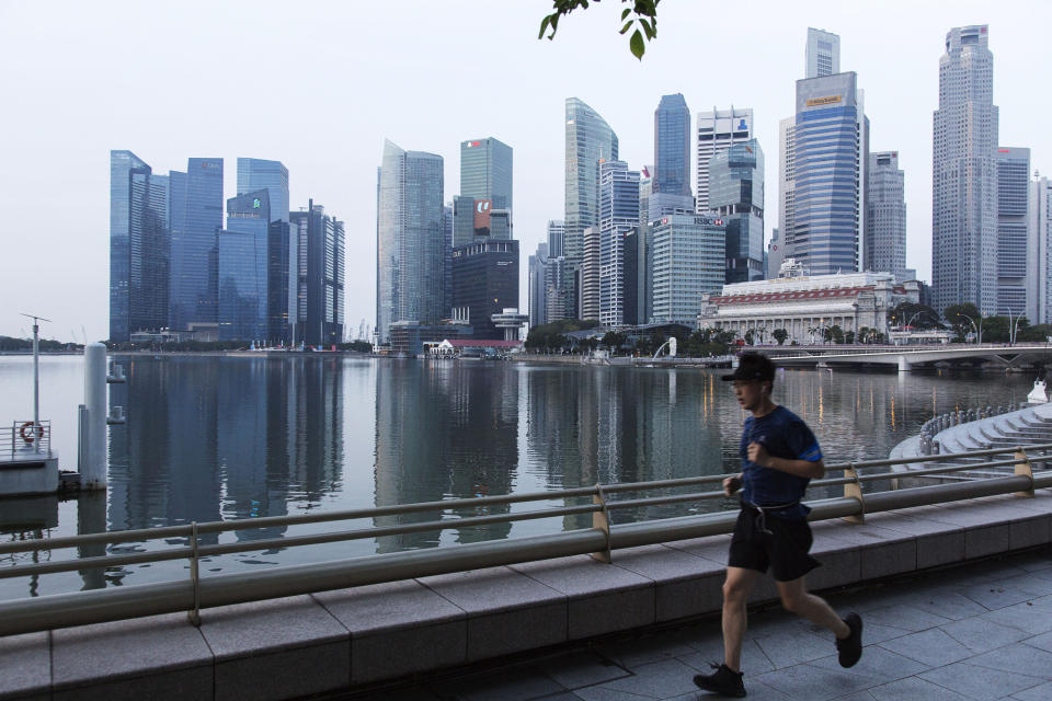 A man runs along a promenade past commercial buildings standing in the central business district in Singapore. (Photo: Getty Images)