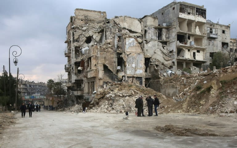 Syrians walk along a destroyed street in the old city of Aleppo on December 17, 2016, as pro-government forces re-open roads that were barricaded to divide rebel and government-held areas