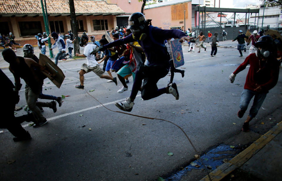 <p>Anti-government protesters run from advancing Venezuelan Bolivarian National Guard officers on the first day of a 48-hour general strike in protest of government plans to rewrite the constitution, in Caracas, Venezuela, Wednesday, July 26, 2017. (Photo: Ariana Cubillos/AP) </p>