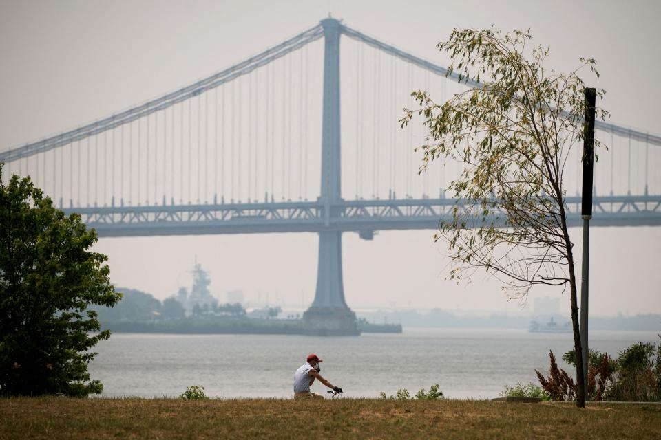 A hazy Benjamin Franklin Bridge, caused by smoke from Canada's wildfires, is seen from Penn Treaty Park in Philadelphia on June 7, 2023. An orange-tinged smog caused by Canada's wildfires shrouded New York on June 7, 2023, obscuring skyscrapers and causing residents to don face masks, as cities along the US East Coast issued air quality alerts.