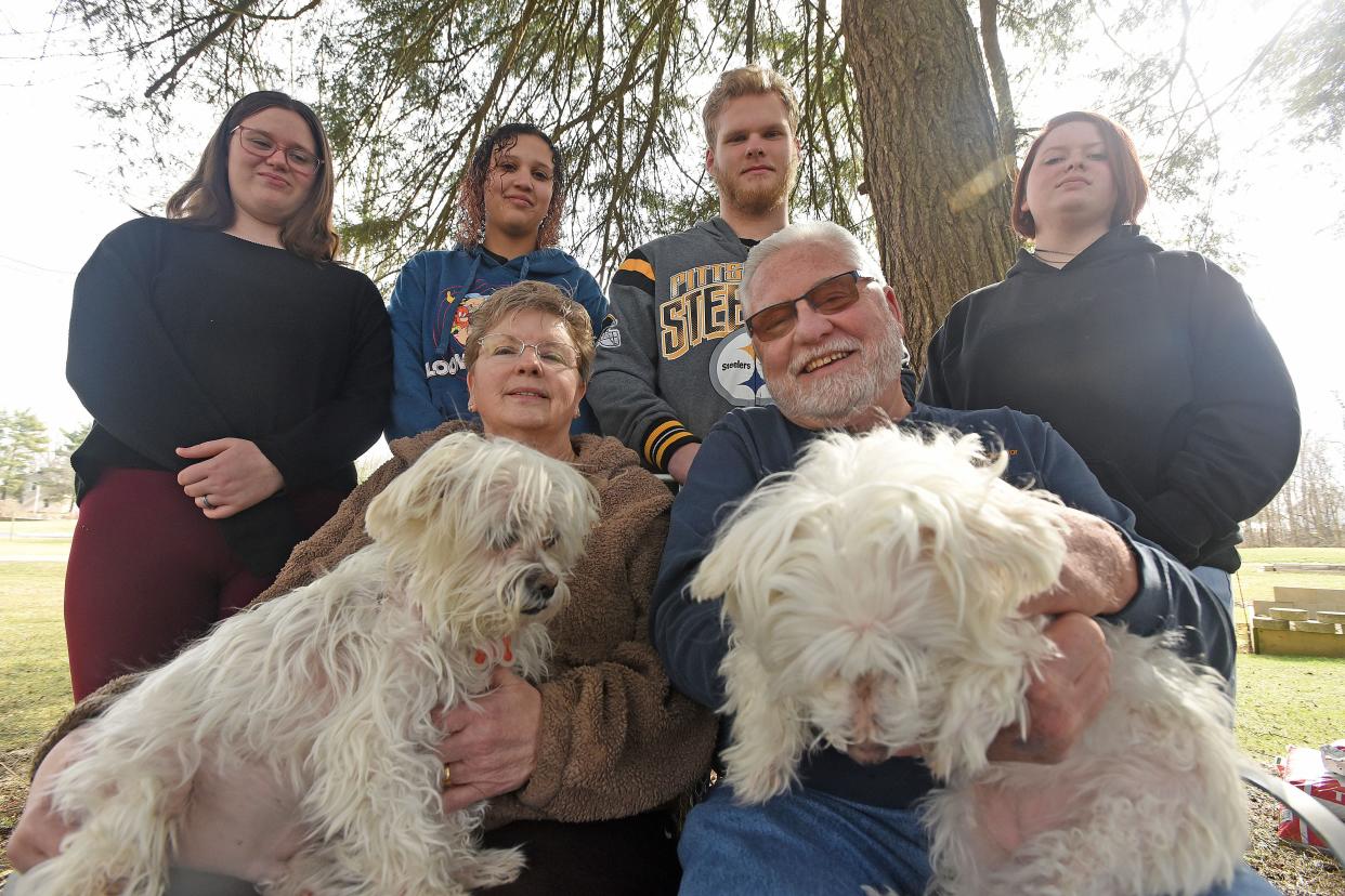 Melinda and Jim Shaum, sitting with dogs Scampy and Daisy, are raising four kids who are not related to them, helping them overcome difficult home lives. Standing, from left, are Aven, Lia, Nick and Alivia. The Shaums have adopted Lia and Nick and plan to adopt Aven and Alivia, too.