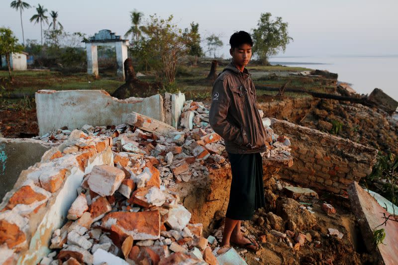 Myo Zaw stands amid the ruins of a monastery after the riverbank is was located on collapsed into the water in Ta Dar U village,Bago, Myanmar