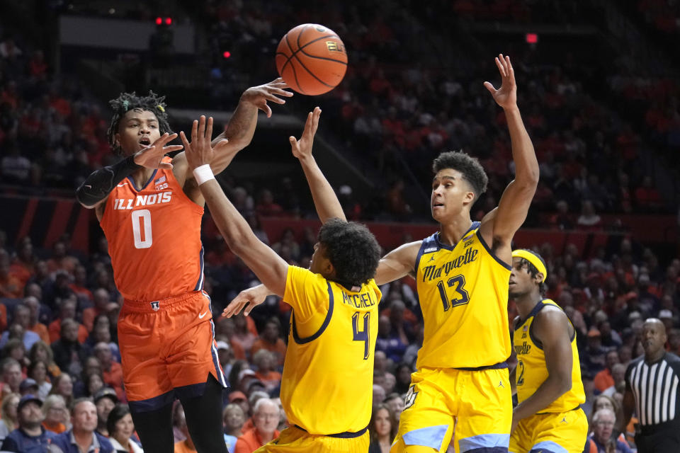 Illinois' Terrence Shannon Jr. (0) passes under pressure from Marquette's Stevie Mitchell (4) and Oso Ighodaro during the first half of an NCAA college basketball game on Tuesday, Nov. 14, 2023, in Champaign, Ill. (AP Photo/Charles Rex Arbogast)