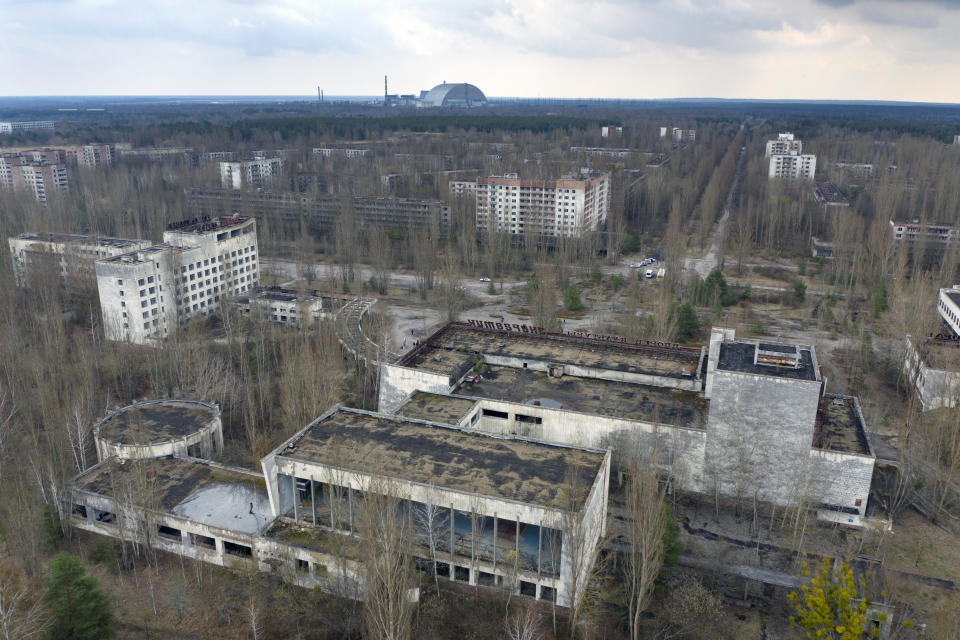 A view of the ghost town of Pripyat with a shelter covering the exploded reactor at the Chernobyl nuclear plant in the background, Ukraine, Thursday, April 15, 2021. The vast and empty Chernobyl Exclusion Zone around the site of the world’s worst nuclear accident is a baleful monument to human mistakes. Yet 35 years after a power plant reactor exploded, Ukrainians also look to it for inspiration, solace and income. (AP Photo/Efrem Lukatsky)