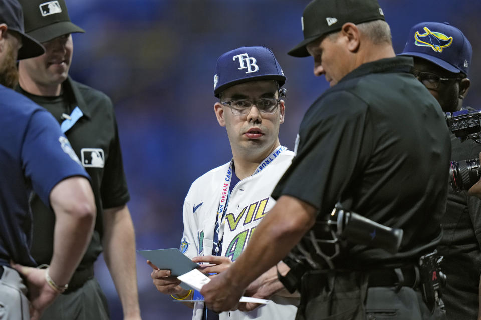19-year-old Austin Majors, center, of Holiday, Fla., delivers the lineup card to the umpires before a baseball game against the Seattle Mariners Friday, Sept. 8, 2023, in St. Petersburg, Fla. The Rays signed Majors to an honorary contract as part of the Children's Dream Fund. (AP Photo/Chris O'Meara)