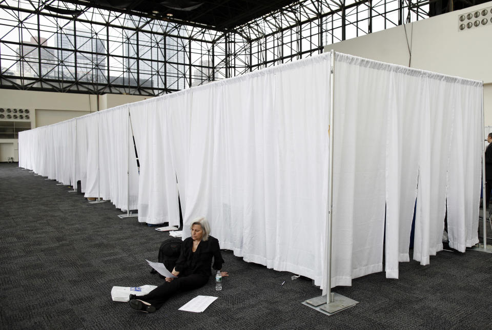A woman looks at a list of employers behind recruiters booths during the 2009 CUNY Big Apple Job Fair in New York