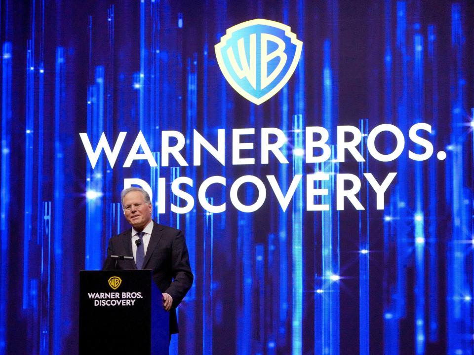 David Zaslav speaks in front of Warner Bros. Discovery logo on blue drape