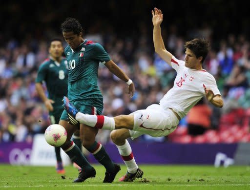 El delantero mexicano Giovani Dos Santos (izq) lucha por el balón contra el defensa suizo Timm Klose, durante la fase clasificatoria a cuartos de los Juegos Olímpicos de Londres, en el estadio Millennium de Cardiff, en Gales este miércoles. (AFP | Glyn Kirk)