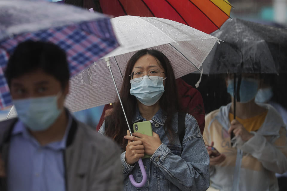 People wearing face masks to help curb the spread of the coronavirus walk in the rain on a street in Beijing, Wednesday, Sept. 23, 2020. Xi Jinping, China's president and the leader of its Communist Party, cast the fight against the virus as an important exercise in international cooperation, an opportunity to "join hands and be prepared to meet even more global challenges." (AP Photo/Andy Wong)