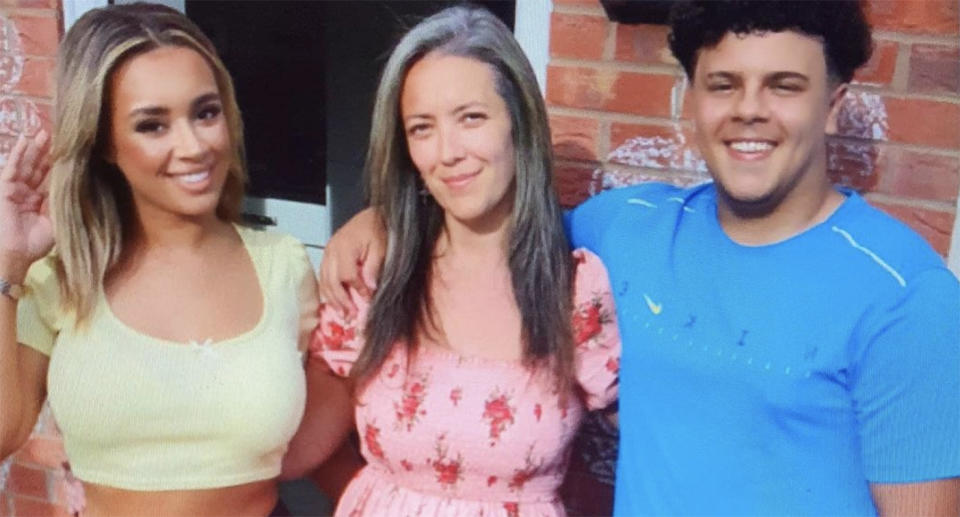 A blonde haired young woman and a dark haired young man smiling with an older women standing in between them.