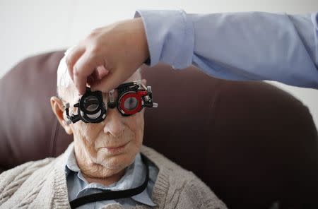 Resident Ernie Mayes, 89, has his eyes checked by Optometrist in his flat at the Colbrooke House care facility run by a private company working on behalf of the local government and housing association in southeast London February 13, 2015. REUTERS/Suzanne Plunkett