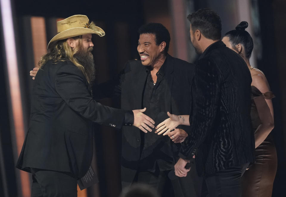 Chris Stapleton, from left, accepts the song of the year award for "Starting Over" from presenters Lionel Richie, and Luke Bryan at the 55th annual CMA Awards on Wednesday, Nov. 10, 2021, at the Bridgestone Arena in Nashville, Tenn. (AP Photo/Mark Humphrey)