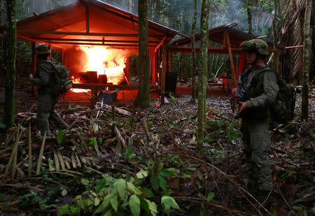 A Colombian anti-narcotics policeman stands guard after burning a cocaine lab, which police said belongs to criminal gangs, in a rural area of Calamar in Guaviare state, Colombia, August 2, 2016. REUTERS/John Vizcaino