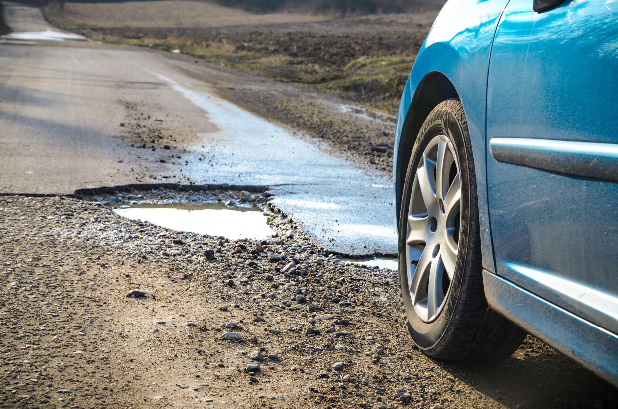 Car and winter pothole on open road