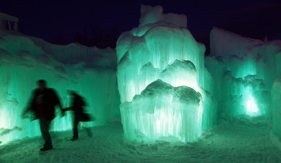 In this photo taken Wednesday Jan. 8, 2014 patrons tour an ice castle at the base of the Loon Mountain ski resort in Lincoln, N.H. The ice castle begins to grow in the fall when the weather gets below freezing and thousands of icicles are made and harvested then placed around sprinkler heads and sprayed with water. The castle will continue to grow as long as the temperatures stay below freezing.(AP Photo/Jim Cole)