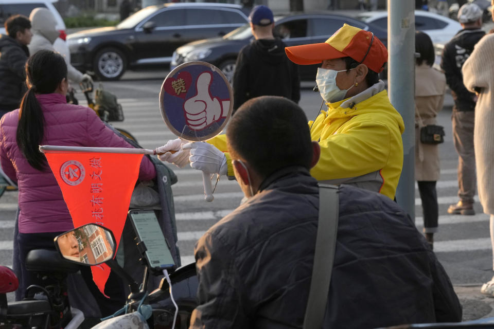 A traffic warden guides traffic flow at a junction in Beijing, China, Wednesday, Oct. 20, 2021. China's capital Beijing has begun offering booster shots against COVID-19, four months before the city and surrounding regions are to host the Winter Olympics. (AP Photo/Ng Han Guan)