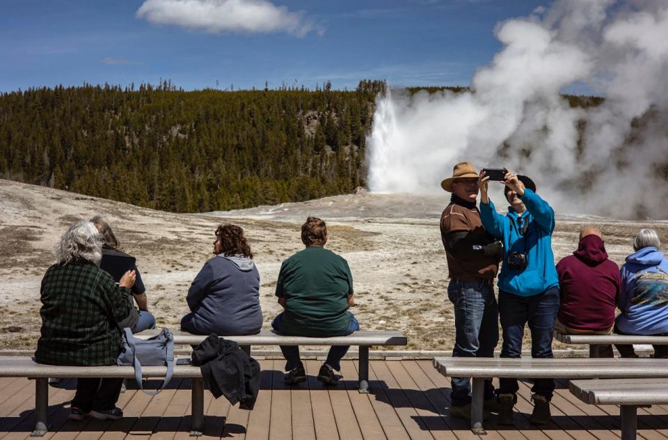 Tourists watch Old Faithful erupt at Yellowstone National Park in April, a month that saw record visitation to the park.