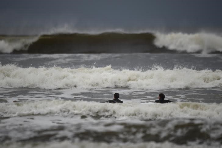 Des surfeurs dans l'Atlantique à la veille de l'arrivée anticipée de la tempête Ophelia à Lahinch en Irlande. L'Irlande se préparait lundi à l'arrivée de la tempête tropicale Ophelia, dont les vents atteignent des pointes à 130 km/h. Les écoles sont restées fermées et l'armée a été mobilisée pour ériger des protections en cas d'inondations subites. /Photo prise le 15 octobre 2017/REUTERS/Clodagh Kilcoyne