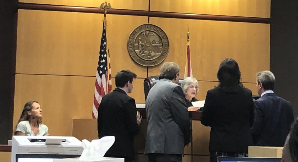 Defendant Suzanna Norris, left, sits in the witness box, while attorneys involved in her case confer with Brevard County Judge Judy Atkin on a legal point.