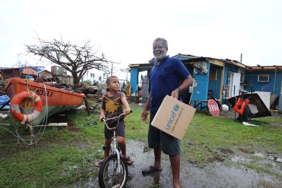 A man and a child stand in front of a destoryed house in Puerto Rico a few days after Hurricane Maria hit the island.