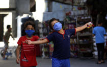 A child wearing a face mask reacts after shopping from a grocery store during a lockdown imposed during the coronavirus pandemic, at Shati refugee camp, in Gaza City, Thursday, Aug. 27, 2020. On Wednesday Gaza's Hamas rulers extended a full lockdown in the Palestinian enclave for three more days as coronavirus cases climbed after the detection this week of the first community transmissions of the virus in the densely populated, blockaded territory. (AP Photo/Adel Hana)