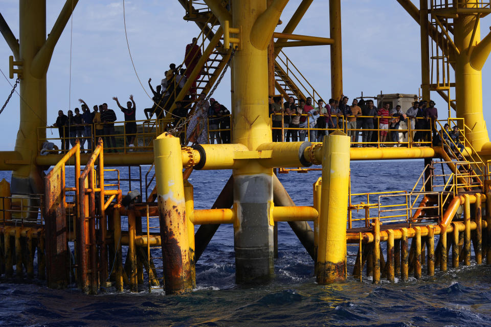 Migrants stand on a petroleum platform in the sea as they wait to be rescued by the Spanish NGO Open Arms lifeguards during a rescue operation in the international waters zone near Tunisia, Mediterranean sea, Saturday, Sept. 17, 2022. Fifty-nine migrants from Syria, Egypt, Sudan and Eritrea, 10 of them minors, were rescued by NGO Open Arms crew members. (AP Photo/Petros Karadjias)