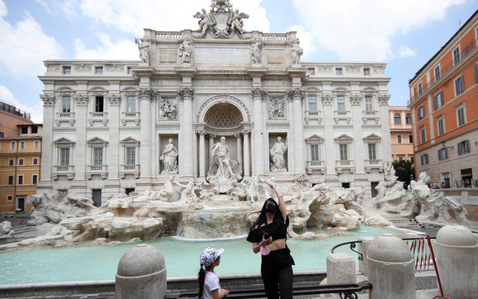 A woman throws a coin in the Trevi fountain, as the region of Lazio becomes a restriction-free "white zone" where only masks and social distancing are required, in Rome, Italy, - Reuters