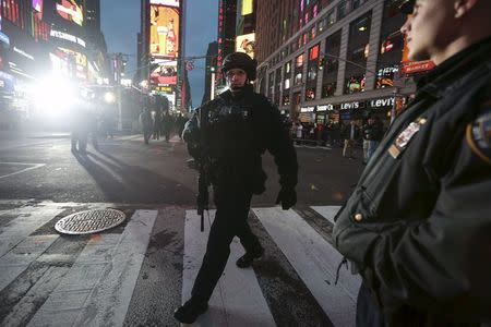 An Emergency Services Unit officer with a long gun walks on patrol through Times Square during New Year's Eve celebrations in the Manhattan borough of New York December 31, 2015. REUTERS/Carlo Allegri