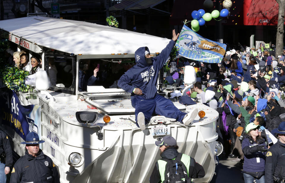 Seattle Seahawks' running back Marshawn Lynch throws pieces of candy while riding on the hood of a vehicle during the Super Bowl champions parade on Wednesday, Feb. 5, 2014, in Seattle. The Seahawks defeated the Denver Broncos 43-8 in NFL football's Super Bowl XLVIII on Sunday. (AP Photo/Ted S. Warren)