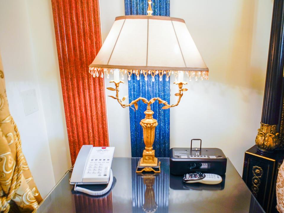 A night stand with a cord phone, a lamp, and an alarm clock in the Aurora Suite in the former Versace Mansion