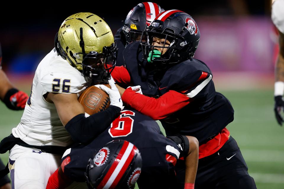 A trio of Aliquippa Quips tackle Bishop McDevitt running back Marquese Williams during Thursday's PIAA Class 4A championship game in Mechanicsburg.