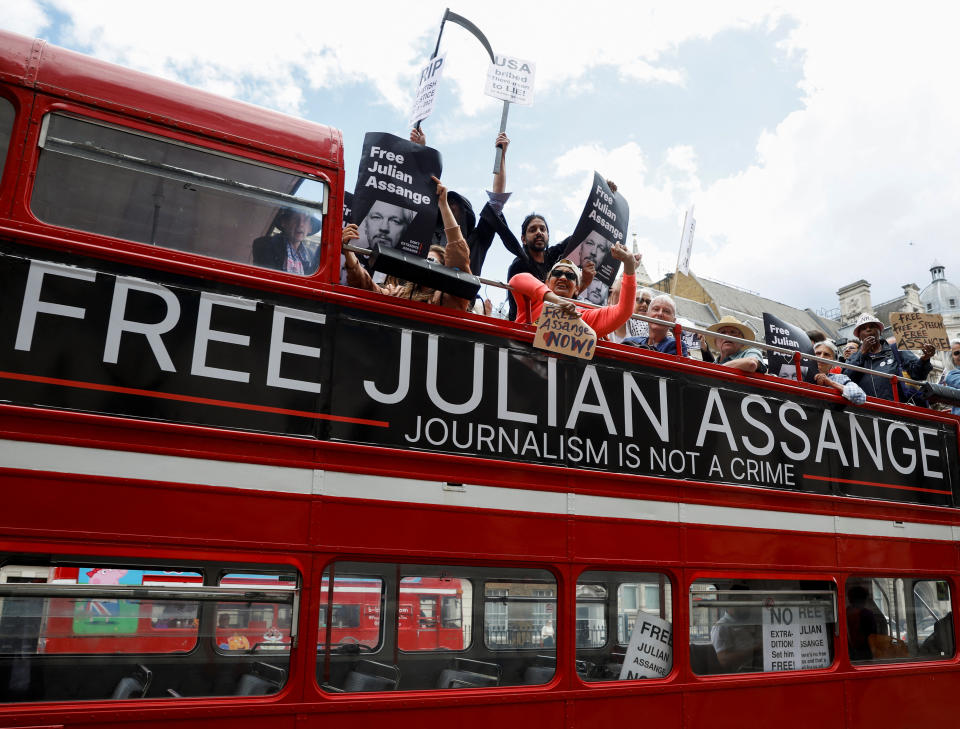 Protesters on a double-decker bus that reads: Free Julian Assange and Journalism Is Not a Crime.