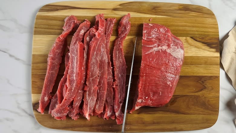 sliced raw flank steak on cutting board