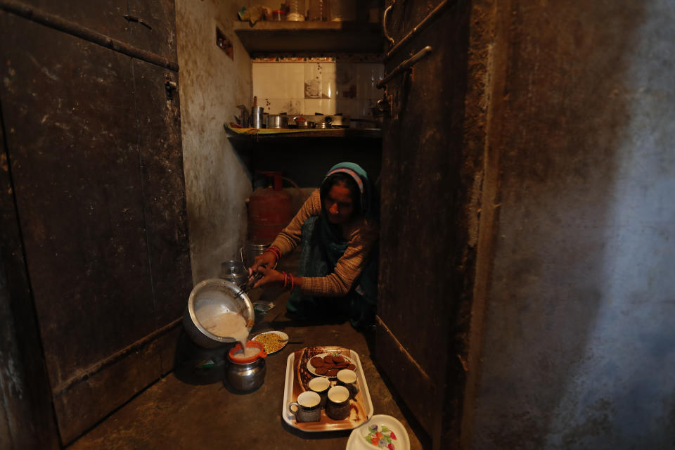 Indian farmer Ram Singh Patel's wife Kantee Devi prepares morning tea for her family members at their village house in Fatehpur district, 180 kilometers (112 miles) south of Lucknow, India, Saturday, Dec. 19, 2020. Patel's day starts at 6 in the morning, when he walks into his farmland tucked next to a railway line. For hours he toils on the farm, where he grows chili peppers, onions, garlic, tomatoes and papayas. Sometimes his wife, two sons and two daughters join him to lend a helping hand or have lunch with him. (AP Photo/Rajesh Kumar Singh)