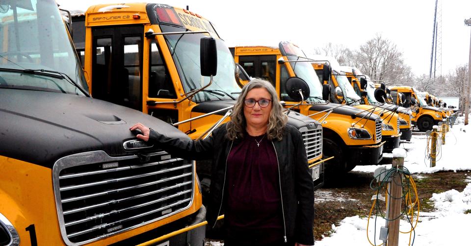 Laurie Sizenore stands in front of a long line of Wooster City Schools' buses.