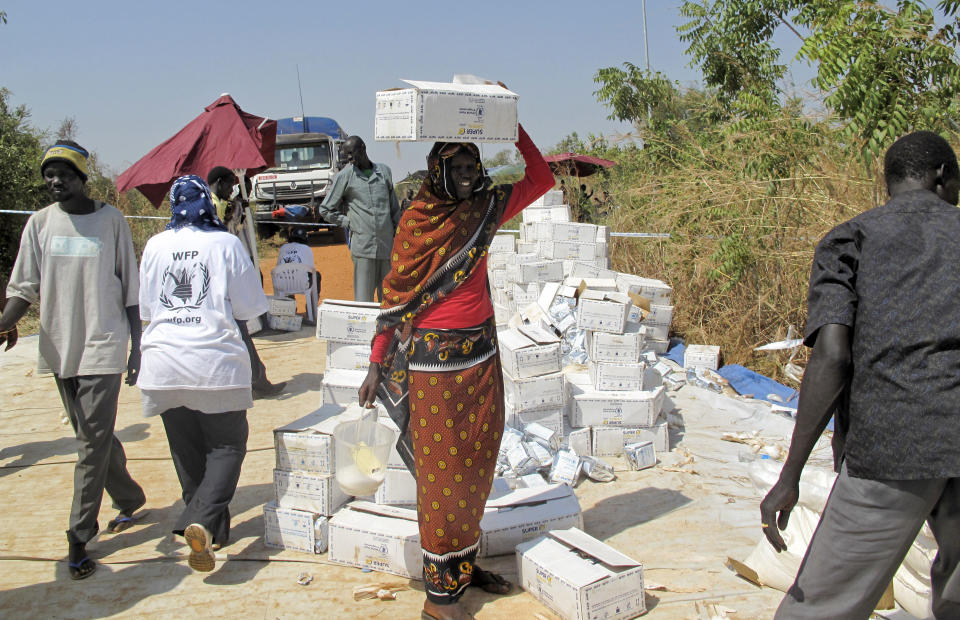 In this photo taken Monday, Dec. 23, 2013 and released by the World Food Programme (WFP), a displaced woman walks with a box of food assistance on her head from a food distribution centre at a U.N. compound in Juba, South Sudan. (AP Photo/WFP, George Fominyen)