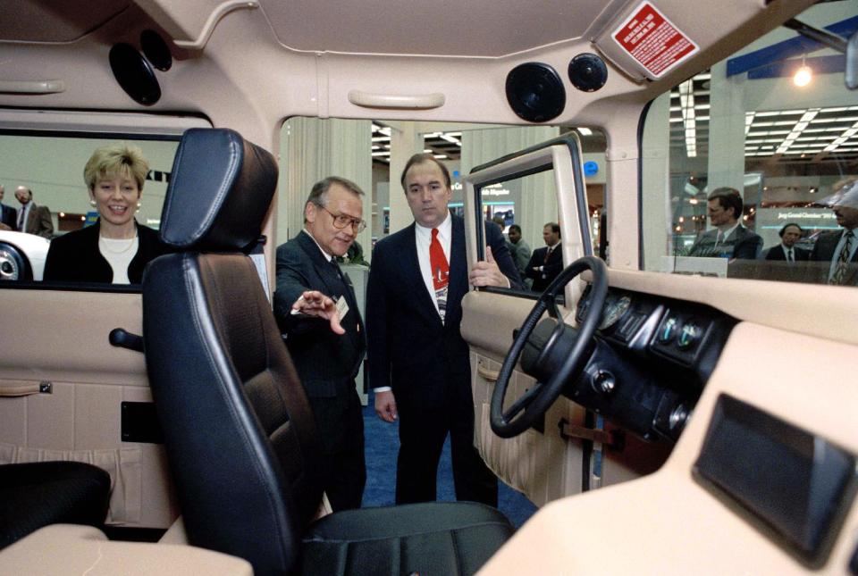 FILE - In this Jan. 8, 1993 file photo, then ASG Inc. chairman Heinz C. Prechter, center, points out the features of a Hummer as then Michigan Gov. John M. Engler and his wife Michelle look inside the vehicle at the North American International Auto Show at Cobo Arena in Detroit. The beefy, military-inspired SUV, a macho icon for fans like Arnold Schwarzenegger and a symbol of ruin for environmentalists, was done in by high gas prices and bad economic times.. (AP Photo/Richard Sheinwald, File)