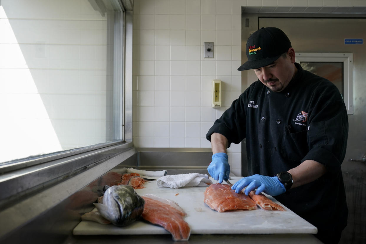 Luis Alvarenga, executive chef at Scoma's, cleans a farm-raised salmon in San Francisco, Monday, March 20, 2023. On April 7, the Pacific Fishery Management Council, the regulatory group that advises federal officials, will take action on what to do about the 2023 season for both commercial and recreational salmon fishing. (AP Photo/Godofredo A. Vásquez)