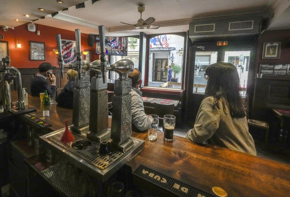 People watch the State Funeral Service of Britain's Queen Elizabeth II on a tv screens, at The Cricketer pub in Paris, Monday, Sept. 19, 2022. The Queen, who died aged 96 on Sept. 8, will be buried at Windsor alongside her late husband, Prince Philip, who died last year. (AP Photo/Michel Euler)