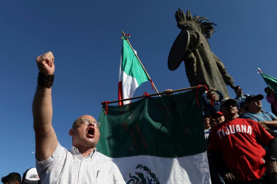 Demonstrators stand under a statue of indigenous Aztec ruler Cuauhtemoc (AP)