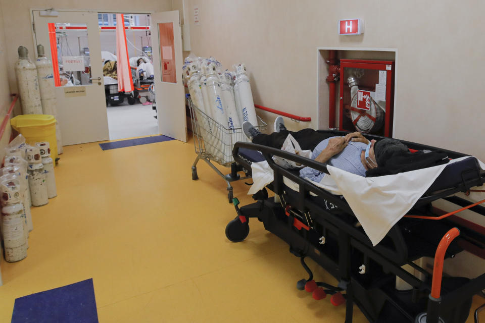 A man lies on a bed in a corridor of the emergency room, turned into a CODIV-19 unit due the high number of cases, at the Bagdasar-Arseni hospital in Bucharest, Romania, Tuesday, Oct. 12, 2021. Romania reported on Tuesday nearly 17,000 new COVID-19 infections and 442 deaths, the highest number of coronavirus infections and deaths in a day since the pandemic started, as the nation's health care system struggles to cope with an acute surge of new cases.(AP Photo/Andreea Alexandru)