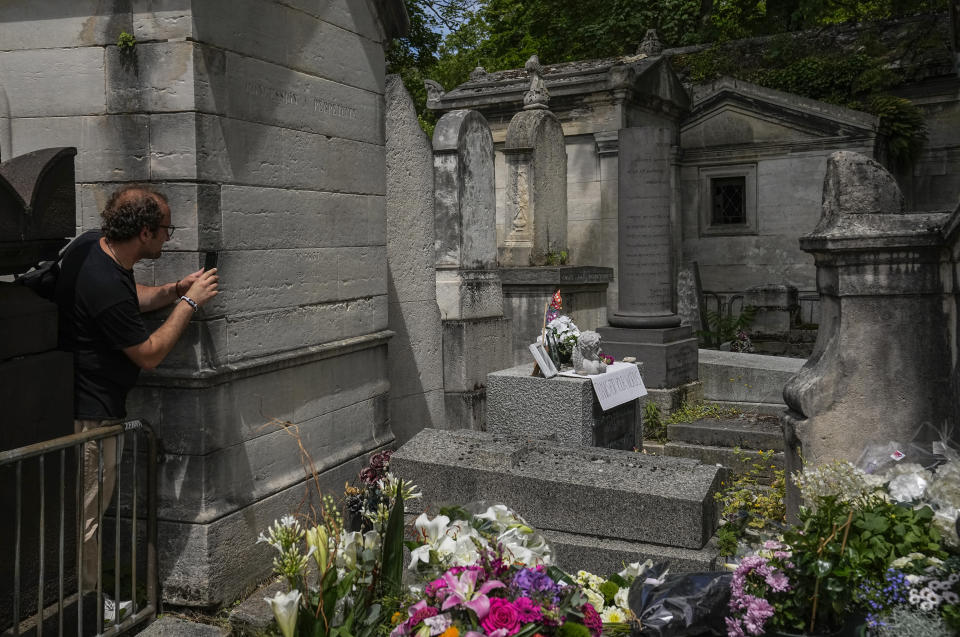 Didimi Sturua of Georgia takes a pictures with his cellphone of the tomb of rock singer Jim Morrison at the Pere-Lachaise cemetery in Paris, Saturday, July 3, 2021. Fans across Europe gathered at the grave of rock legend Jim Morrison to mark the 50th anniversary of his death. (AP Photo/Michel Euler)