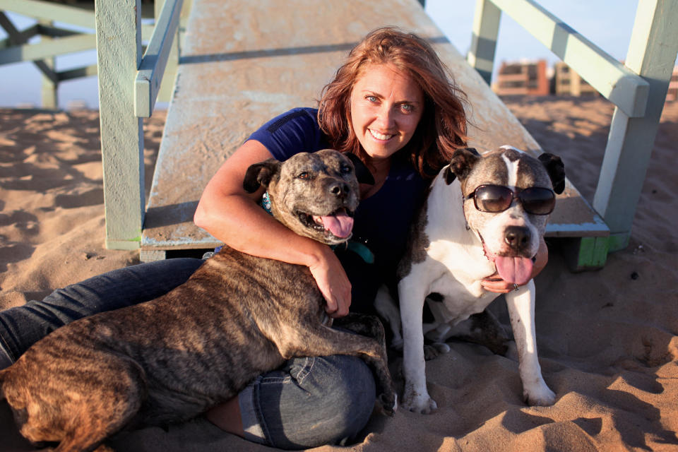 This June 21, 2013 photo courtesy of Lori Fusaro shows photographer Lori Fusaro hugging her two dogs: Gabby, 10, left, and Sunny, 17, at Playa del Rey in Los Angeles. Fusaro is is working on "Silver Hearts," a photo book of old dogs. She plans to turn proceeds over to rescues that save old dogs and also hopes the book will encourage others to adopt old dogs. (AP Photo/Lori Fusaro)