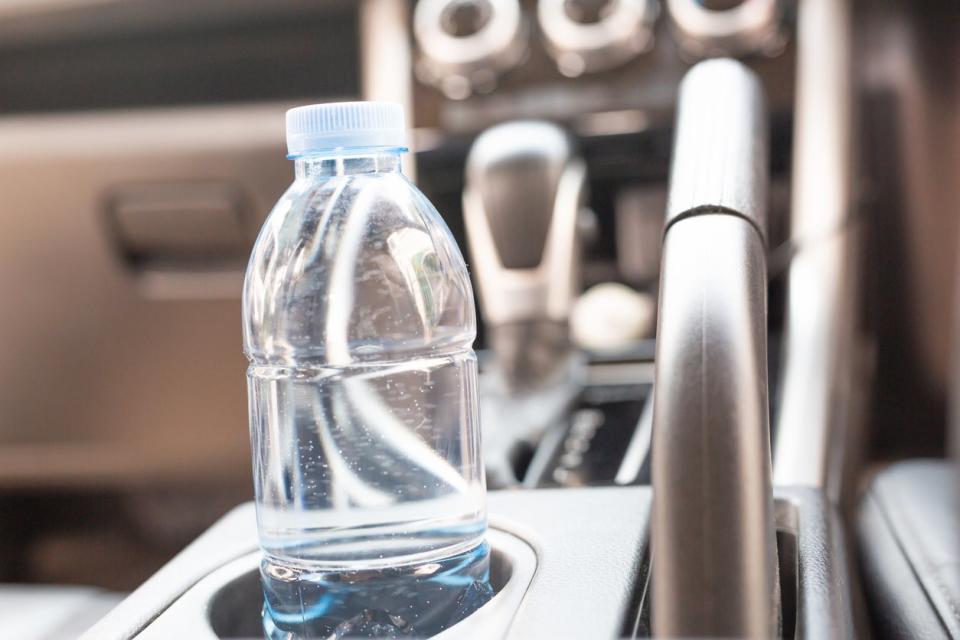 A bottle of water in a car's center console cup holder.