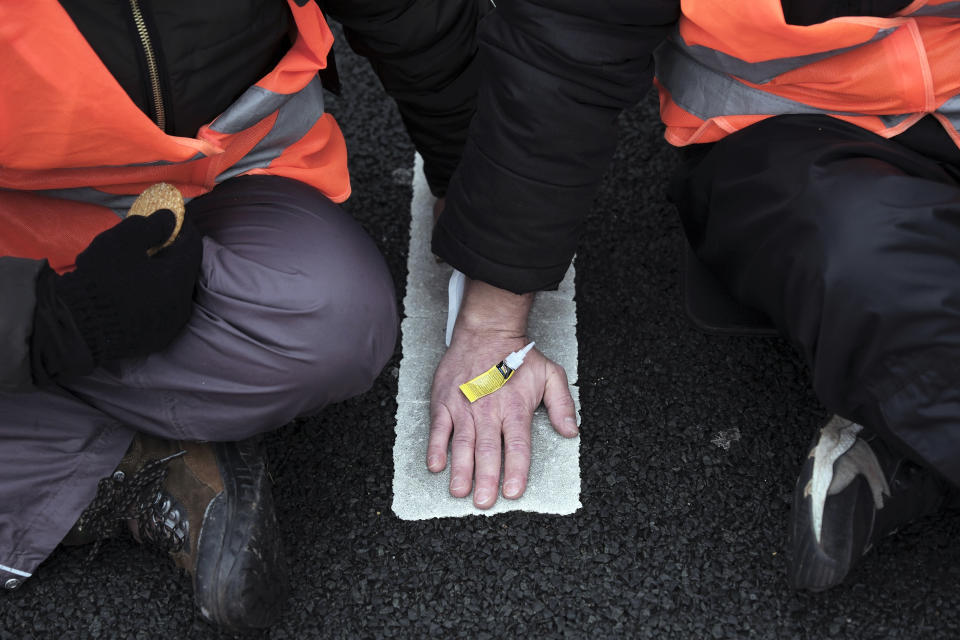 Climate activists glue their hands to the ground while blocking the main highway around Amsterdam near the former headquarters of a ING bank to protest its financing of fossil fuels, Saturday, Dec. 30, 2023. Protestors walked onto the road at midday, snarling traffic around the Dutch capital in the latest road blockade organized by the Dutch branch of Extinction Rebellion. (AP Photo/Patrick Post)